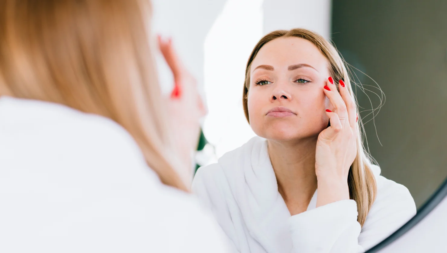 Woman examining her facial skin and features in a mirror