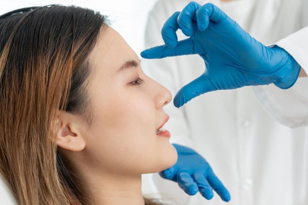 Surgeon assessing a woman's nose profile before rhinoplasty surgery