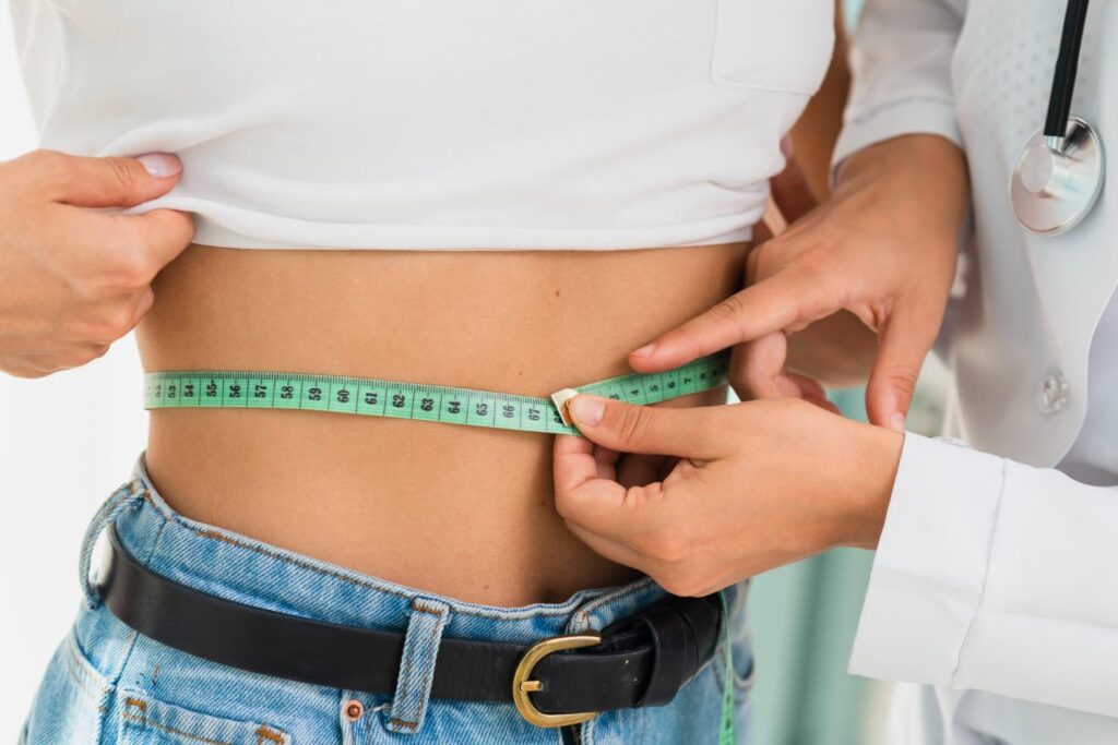 Doctor measuring a patient’s waist to assess candidacy for a gastric sleeve revision