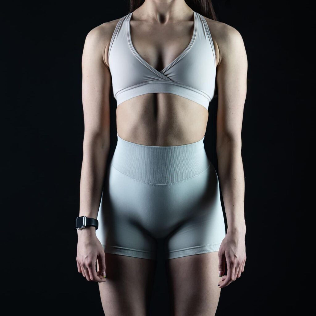 Woman with a toned midriff in activewear after liposuction recovery